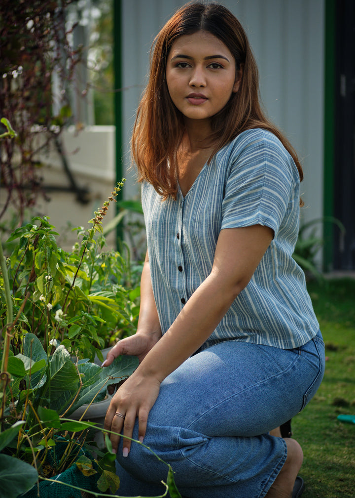 a woman wearing a blue shirt sitting in a garden